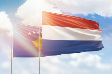 Sunny blue sky and flags of netherlands and kosovo