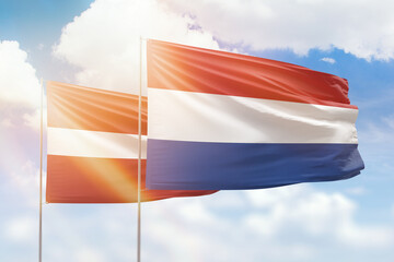 Sunny blue sky and flags of netherlands and latvia