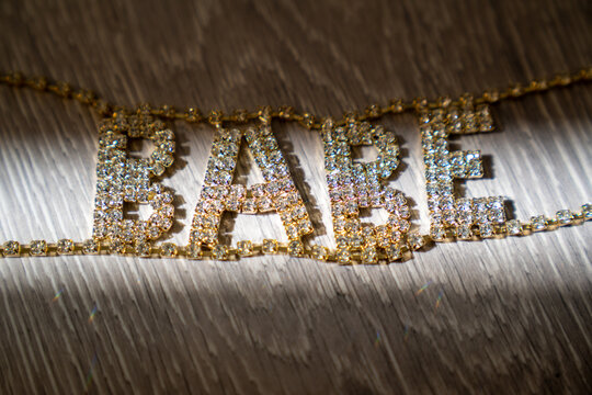 close up of a beautiful gold glitter texture, word baby, golden jewelry necklace on the wooden background 