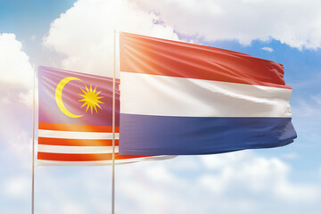Sunny blue sky and flags of netherlands and malaysia
