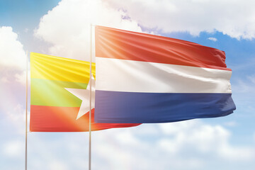 Sunny blue sky and flags of netherlands and myanmar