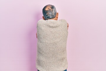 Handsome senior man with beard wearing casual sweater and glasses hugging oneself happy and positive from backwards. self love and self care