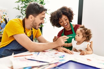 Couple and daughter smiling confident painting child nose at art studio
