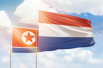 Sunny blue sky and flags of netherlands and north korea