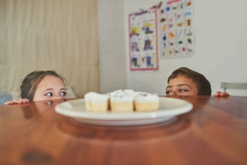 Obraz na płótnie Canvas I spy with my little eye.... Cropped shot of two naughty children eyeing a plate of cupcakes.