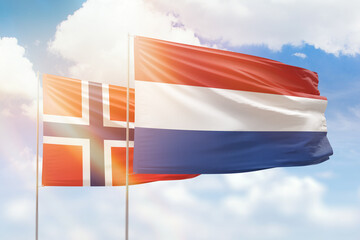 Sunny blue sky and flags of netherlands and norway