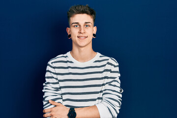 Young caucasian boy with ears dilation wearing casual striped shirt happy face smiling with crossed arms looking at the camera. positive person.