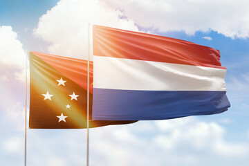 Sunny blue sky and flags of netherlands and papua new guinea