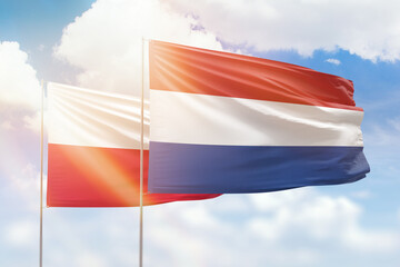 Sunny blue sky and flags of netherlands and poland