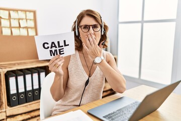 Middle age brunette woman wearing operator headset holding call me banner bored yawning tired...