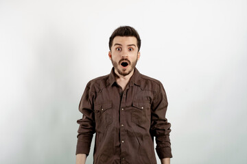Portrait of man wearing brown shirt posing isolated over white background afraid and shocked with surprise and amazed expression, fear and excited face.