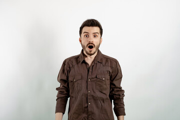Obraz premium Portrait of man wearing brown shirt posing isolated over white background afraid and shocked with surprise and amazed expression, fear and excited face.