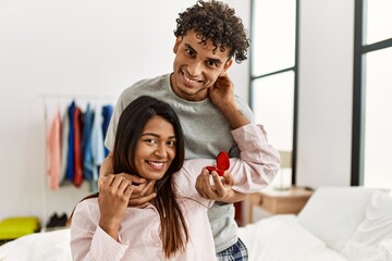 Obraz premium Young latin couple on marriage proposal holding engagement ring at the bedroom.