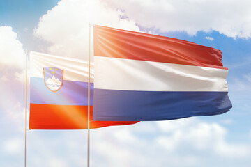 Sunny blue sky and flags of netherlands and slovenia