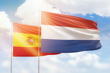 Sunny blue sky and flags of netherlands and spain