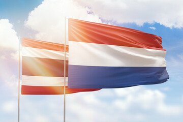 Sunny blue sky and flags of netherlands and thailand