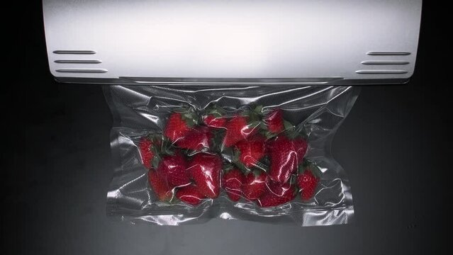 vacuum packaging machine packs strawberries in a plastic bag. High quality FullHD footage
