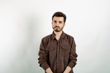 Fototapeta premium Portrait of man wearing brown shirt posing isolated over white background crying wipes tears losing his job. I don't know.