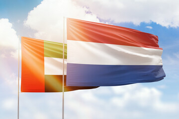 Sunny blue sky and flags of netherlands and uae