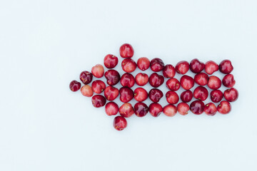 Sweet red cherries on a white background in the shape of an arrow. Ripe fresh red sweet cherry isolated on white background