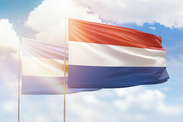 Sunny blue sky and flags of netherlands and argentina