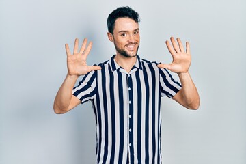 Young hispanic man wearing casual clothes showing and pointing up with fingers number ten while smiling confident and happy.