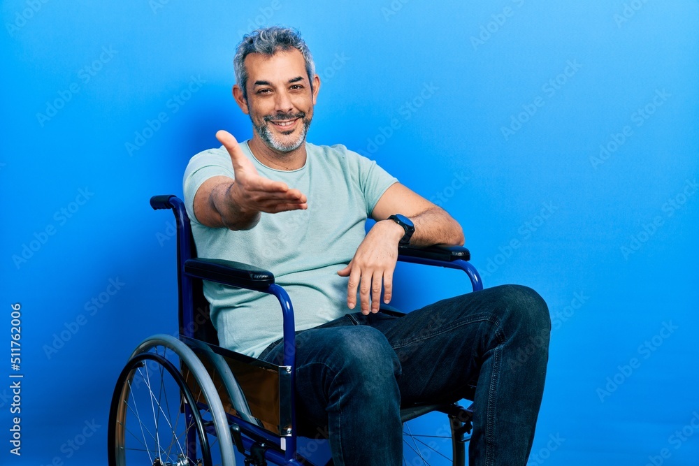 Canvas Prints handsome middle age man with grey hair sitting on wheelchair smiling cheerful offering palm hand giv