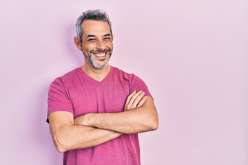 Handsome middle age man with grey hair wearing casual pink t shirt happy face smiling with crossed arms looking at the camera. positive person.