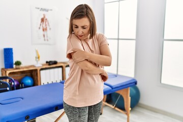Middle age hispanic woman with arm pain at physiotherapy clinic