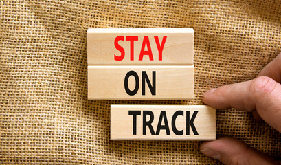 Stay on track symbol. Concept words Stay on track on wooden blocks on a beautiful canvas table canvas background. Businessman hand. Business, motivational and stay on track concept. Copy space.