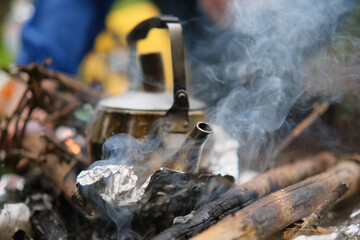 Teapot over the fire. Beautiful campfire in a tourist camp in the summer forest.