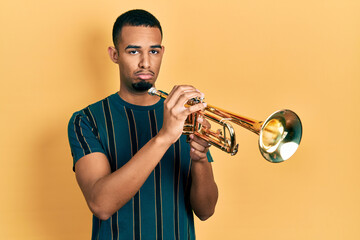 Young african american man playing trumpet depressed and worry for distress, crying angry and...