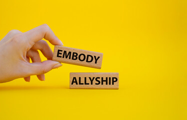 Embody Allyship symbol. Concept word Embody Allyship on wooden blocks. Beautiful blue background. Businessman hand. Business and Embody Allyship concept. Copy space