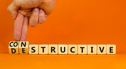 Destructive or constructive symbol. Businessman turns cubes changes the concept word Destructive to...