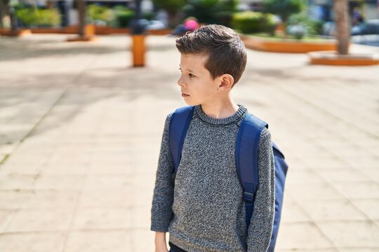 Blond child student standing with serious expression at park