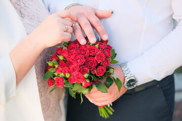 Hands and rings on wedding red bouquet