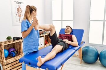 Fototapeta na wymiar Young hispanic physioterapist woman make legs rehab treatment to man at the clinic.