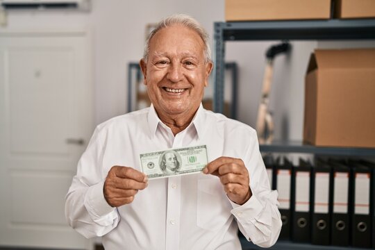 Senior man ecommerce business worker holding dollar at office