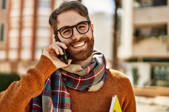Caucasian man with beard having a conversation speaking on the phone outdoors on a sunny day