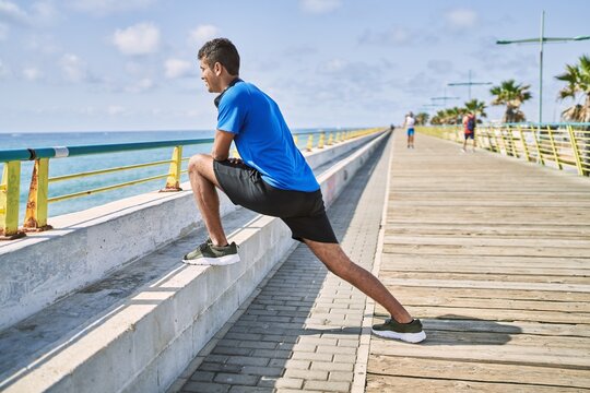 Young hispanic man stretching leg muscles outdoors
