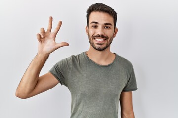 Young hispanic man with beard wearing casual t shirt over white background showing and pointing up...
