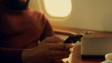 Guy using mobile phone in private jet closeup. Smiling bearded man hold in hands - Powered by Adobe