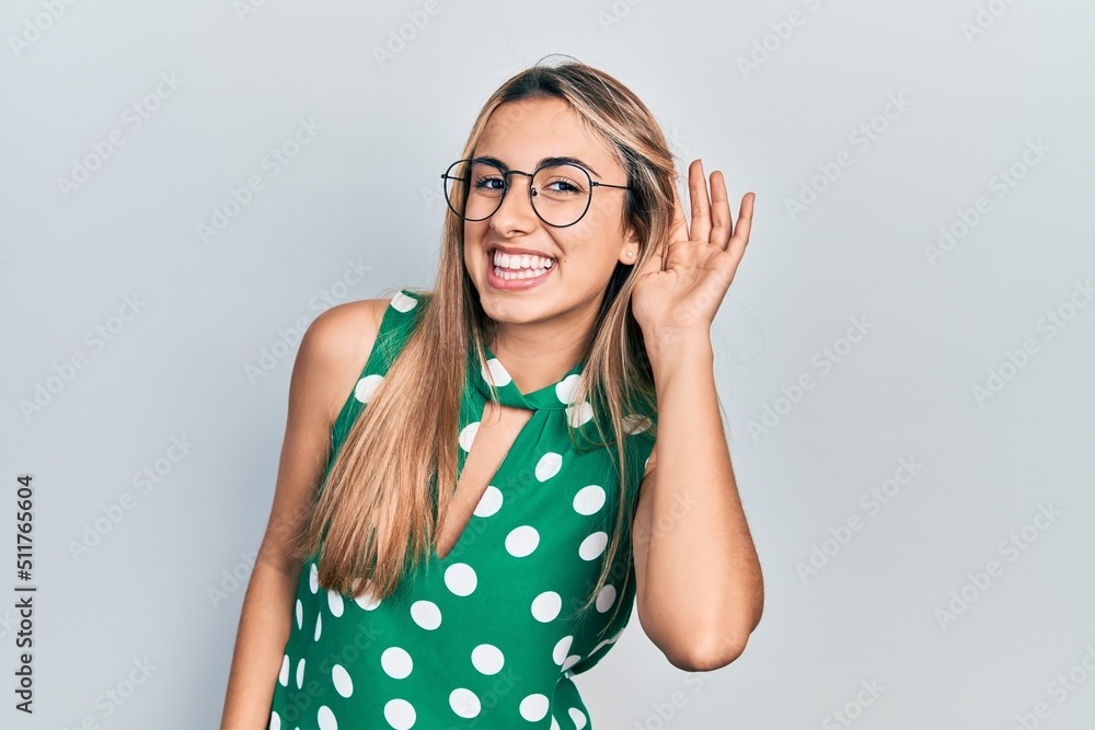 Sticker Beautiful hispanic woman wearing elegant shirt and glasses smiling with hand over ear listening an hearing to rumor or gossip. deafness concept.