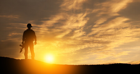 Obraz premium Silhouette of soldier standing against the backdrop of a sunset. Greeting card for Veterans Day, Memorial Day, Independence Day. USA celebration. Concept - patriotism, protection, remember honor.