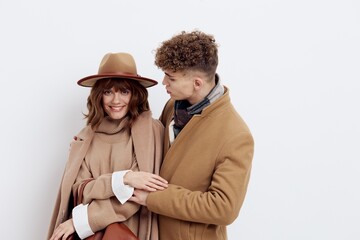 a happy couple a man and a woman are standing in stylish autumn clothes on a white background close to each other and a man looks tenderly at a woman