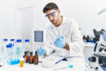 Fototapeta premium Handsome hispanic man using scientific mortar at laboratory