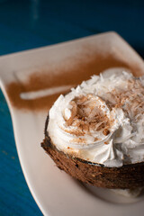 Dessert with caramel, cinnamon and meringue. Served in a coconut shell

