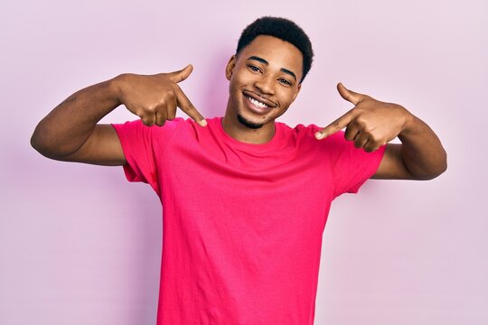 Young african american man wearing casua t shirt looking confident with smile on face, pointing oneself with fingers proud and happy.