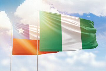 Sunny blue sky and flags of nigeria and chile