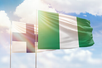 Sunny blue sky and flags of nigeria and finland